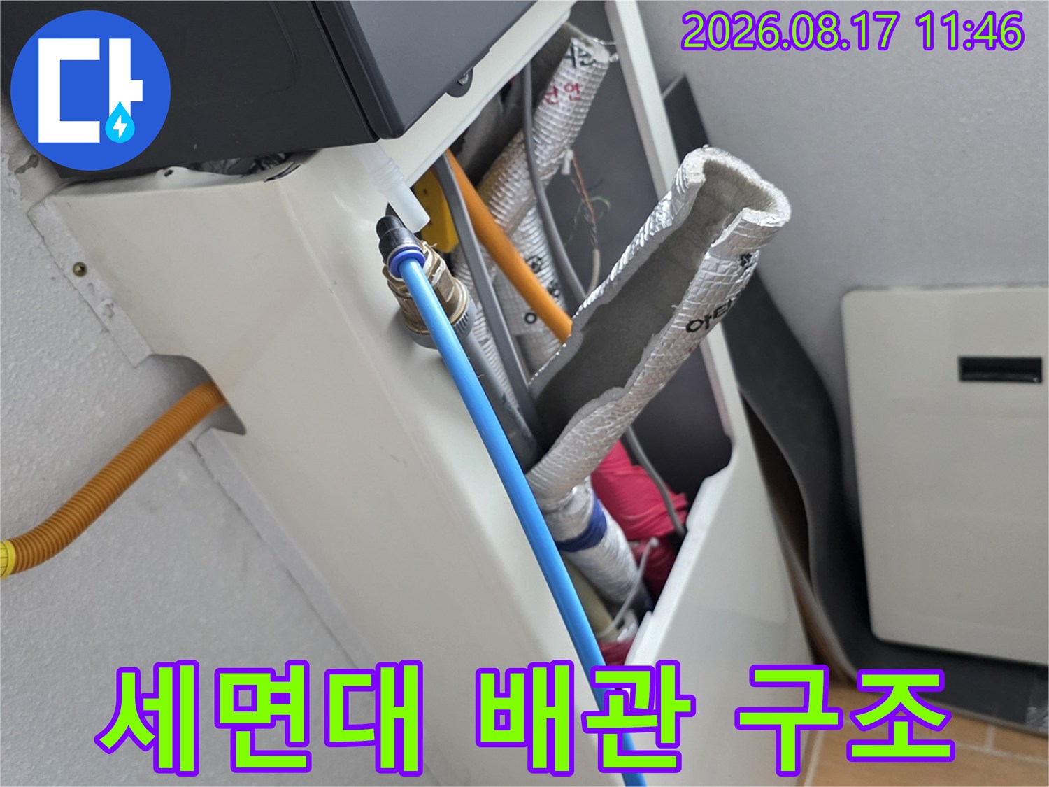 파란색 호스와 은박 보온재가 씌워진 세면대 하부 배관의 상세 모습