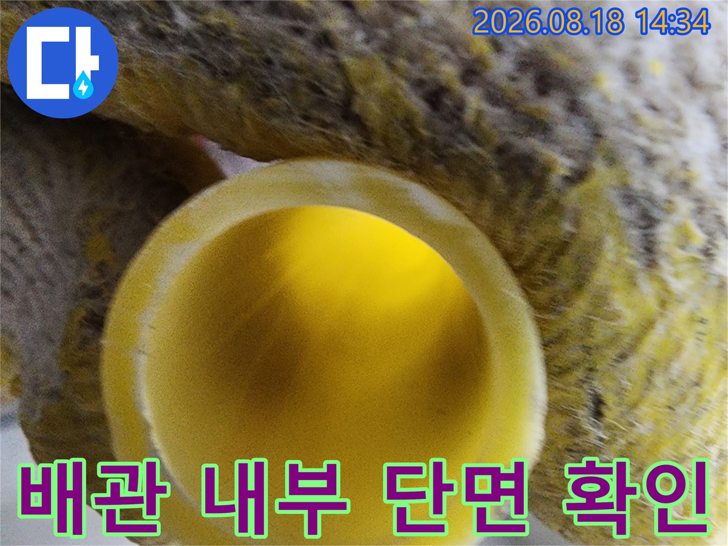 작업용 장갑을 낀 손이 잡고 있는 노란색 배관 입구