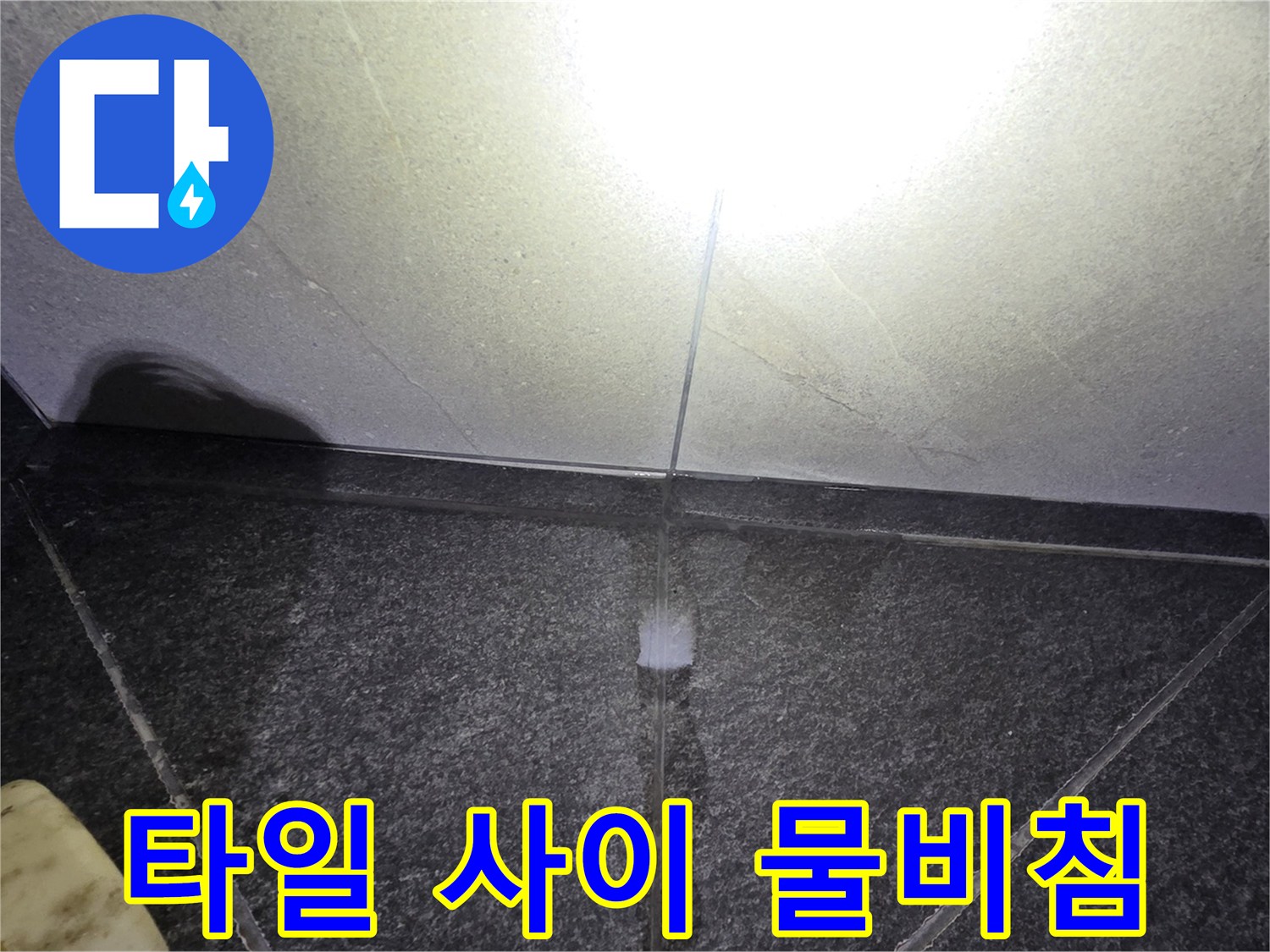 어두운 조명 아래 보이는 타일 경계의 물기
