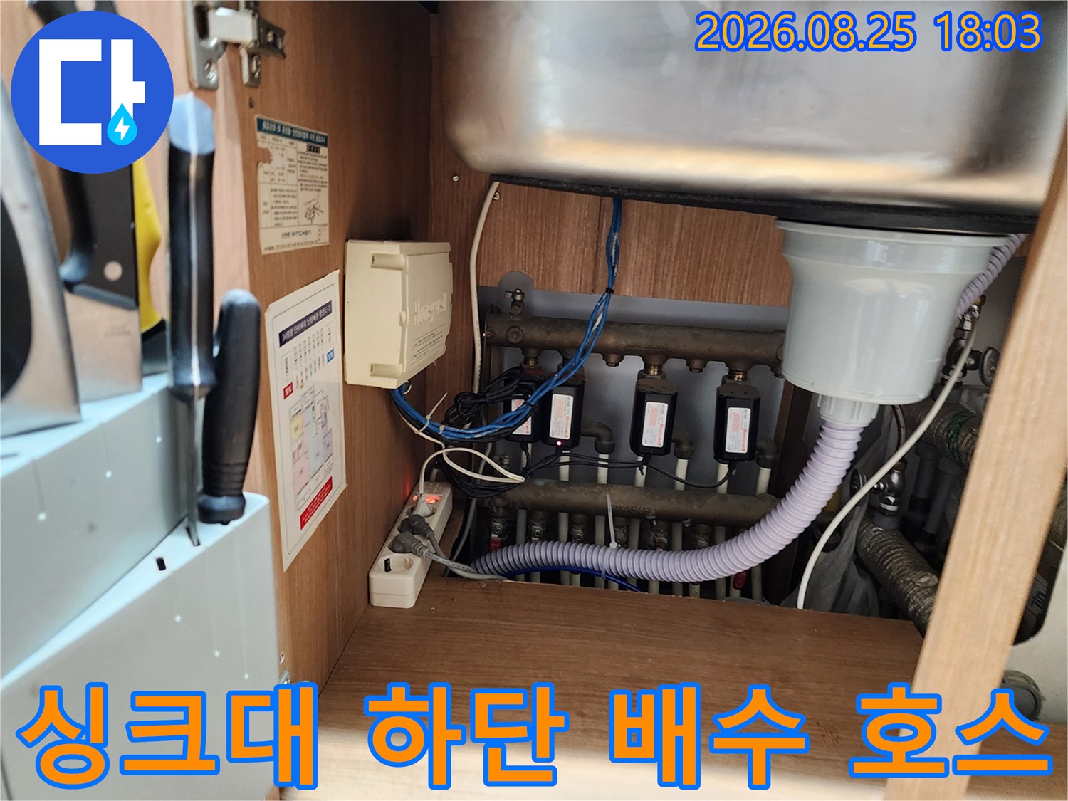 싱크대 하부장 내부의 굴곡진 배수 호스와 연결 부위 상세 모습