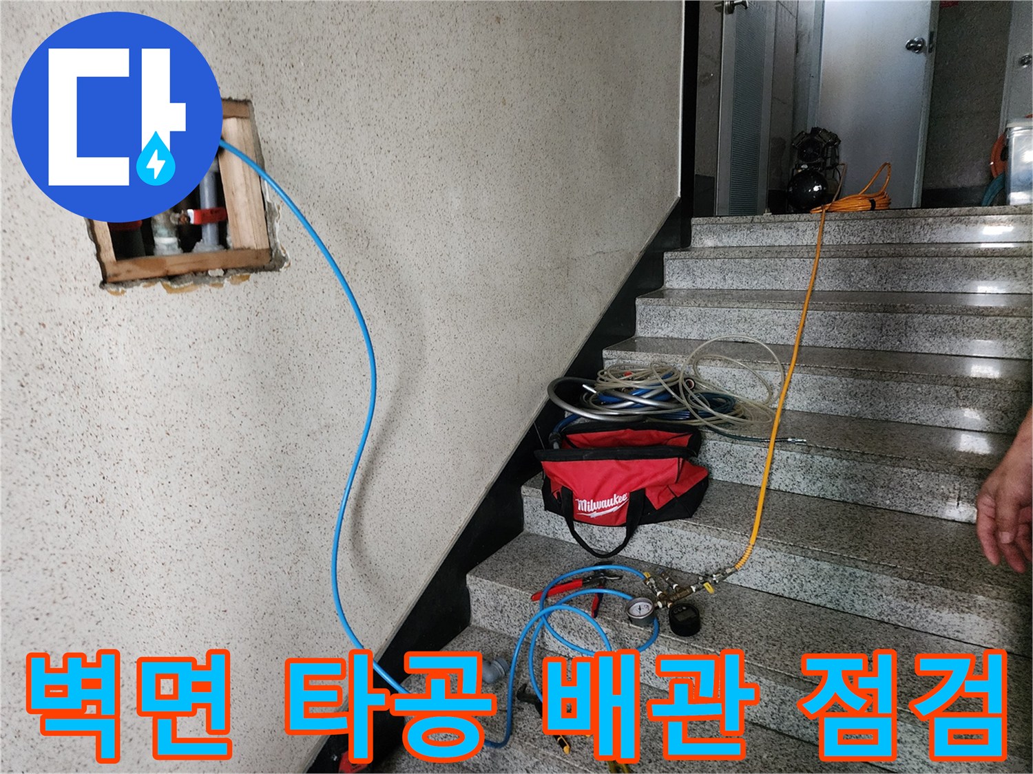 벽 내부 배관에 연결된 파란색 검사 라인과 타공 부위