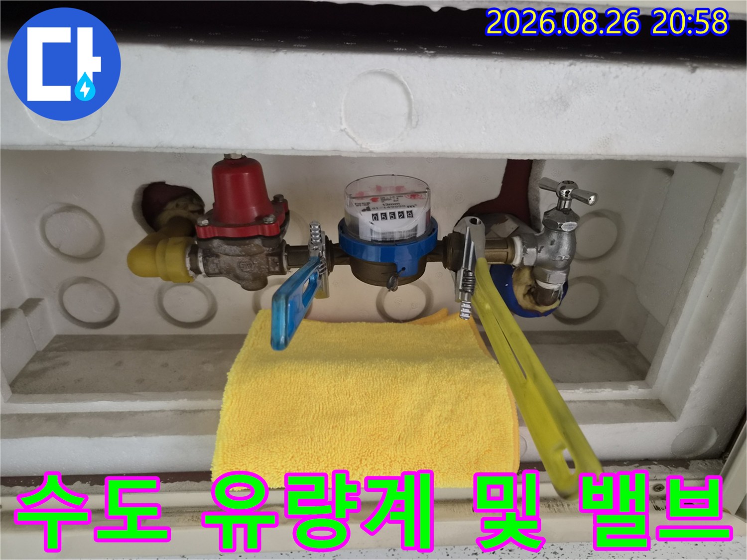 금속 재질의 수도 배관과 유량계가 설치된 모습입니다.