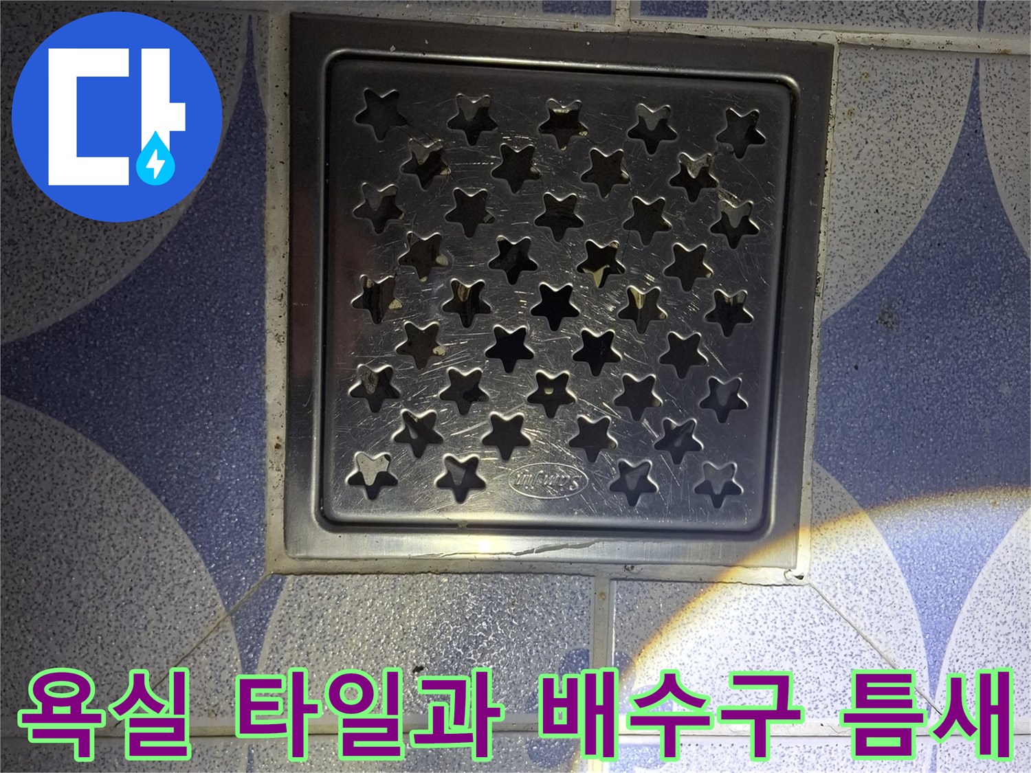 푸른색 패턴 타일 사이의 스테인리스 배수구 덮개