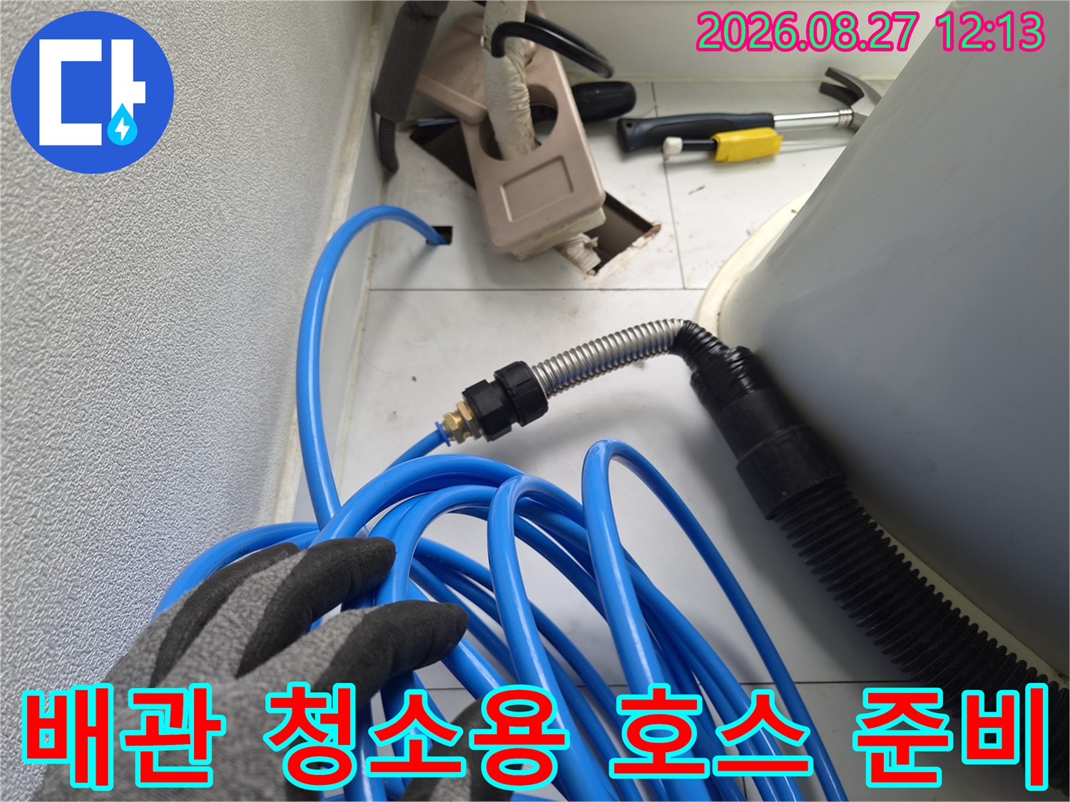 파란색 호스와 금속 자바라가 연결된 배관 세척 장비의 모습입니다.