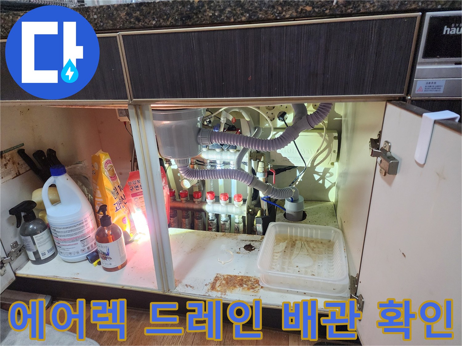 싱크대 아래쪽으로 연결된 흰색 주름관과 분리된 배수 부품들