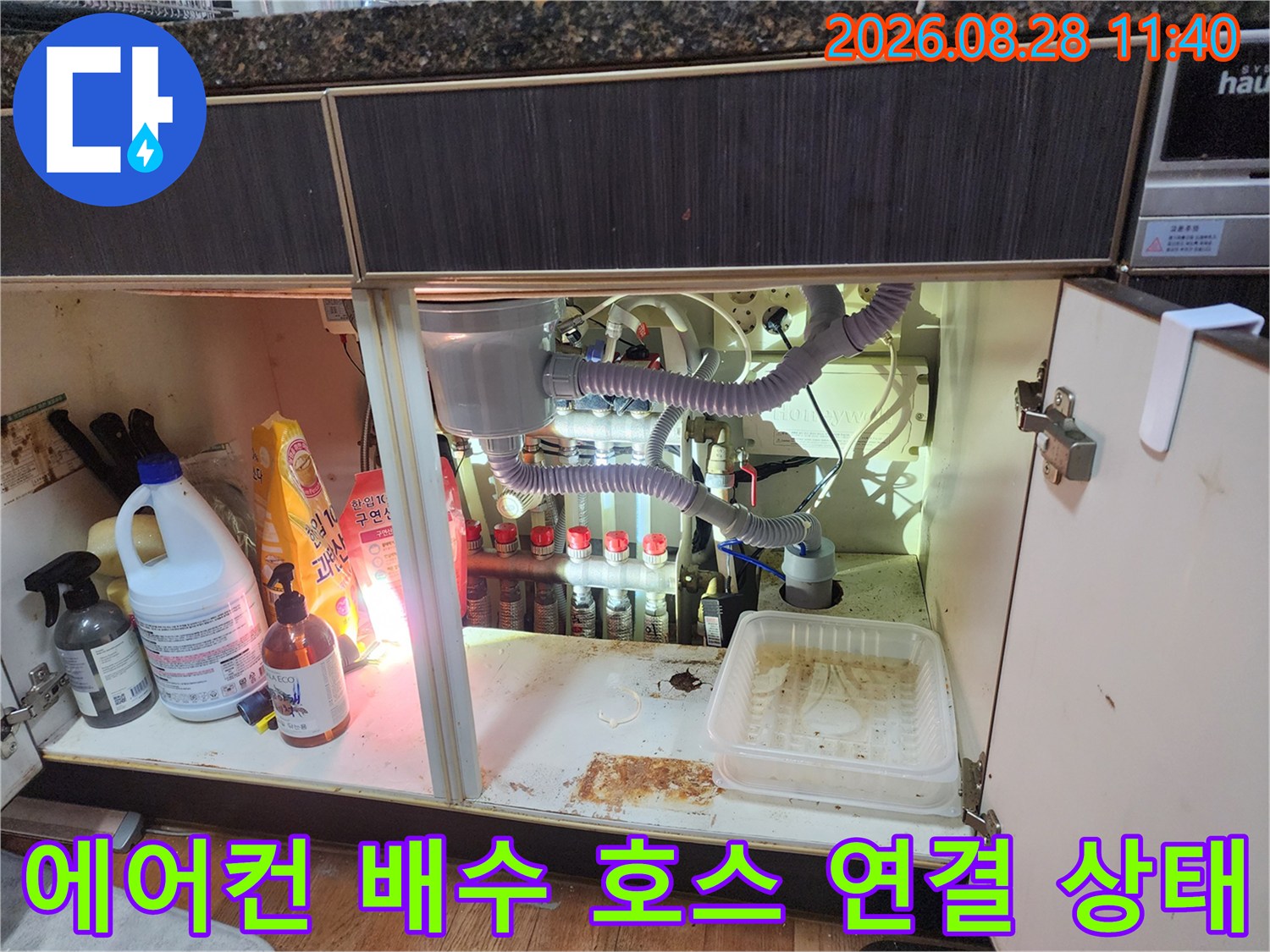 싱크대 하부장 내부에 설치된 에어컨 드레인 및 싱크대 배수 호스