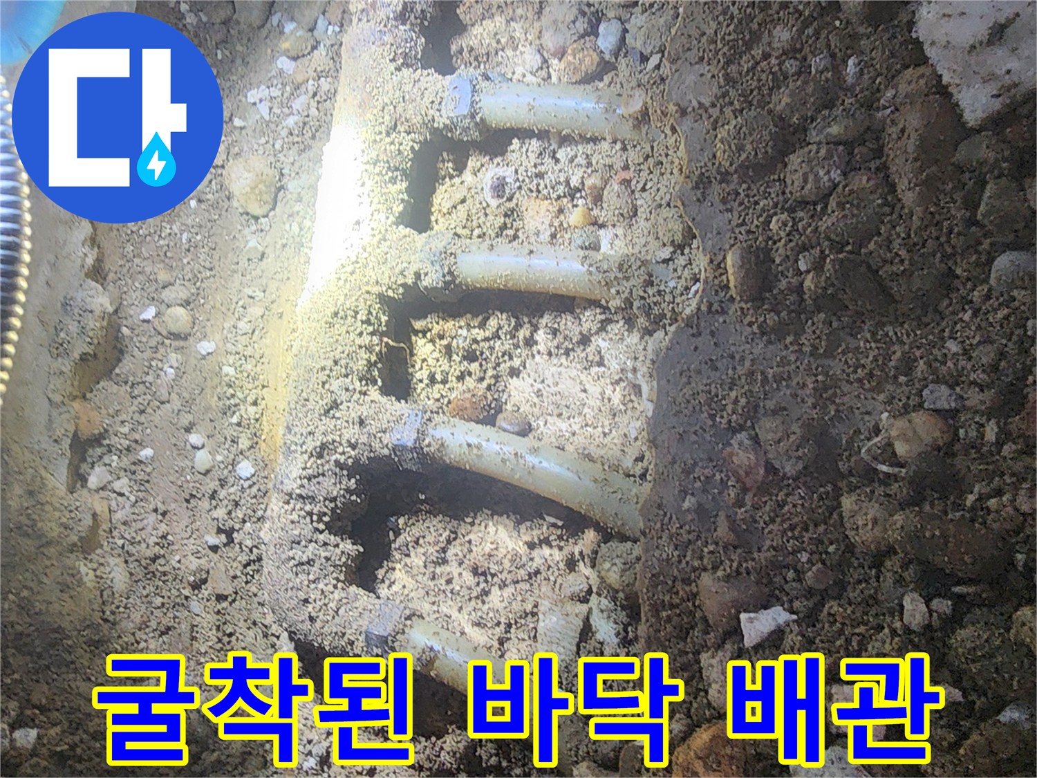공사 중 드러난 흙과 자갈 속의 노후 배관