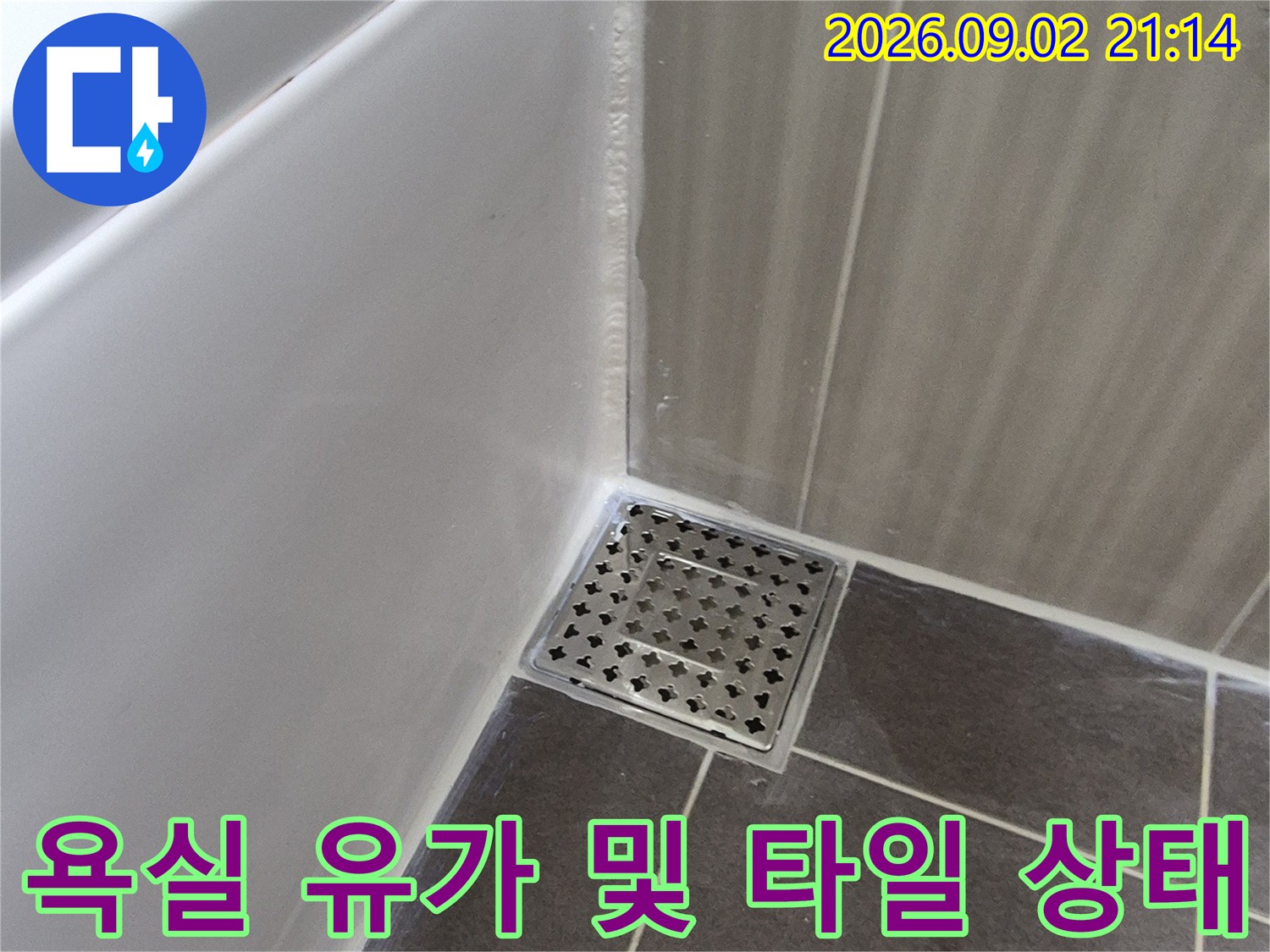금속 배수구 덮개와 회색 타일의 접합 부위