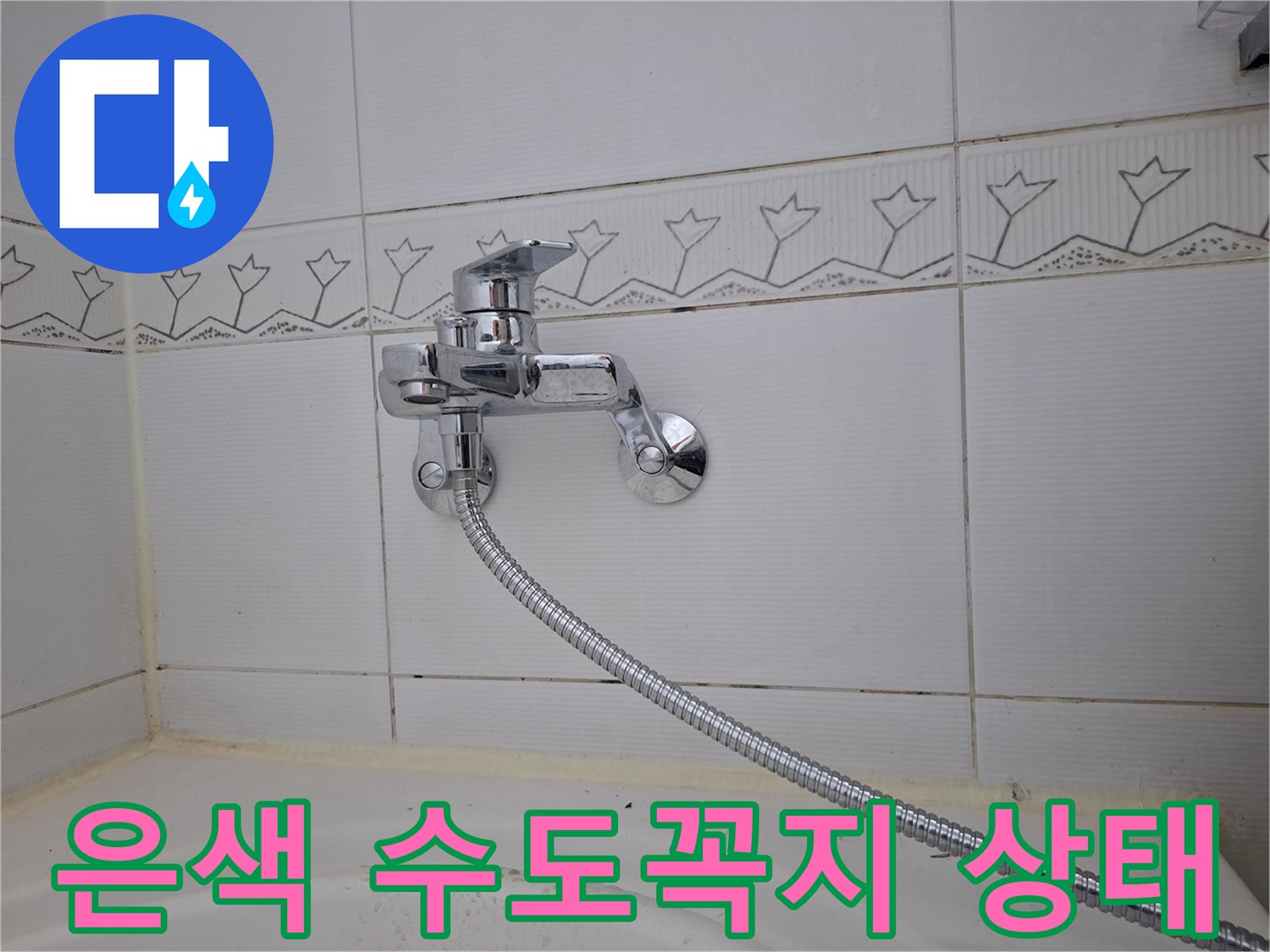 타일 벽면에 고정된 크롬 수전과 샤워기 호스 연결 부위