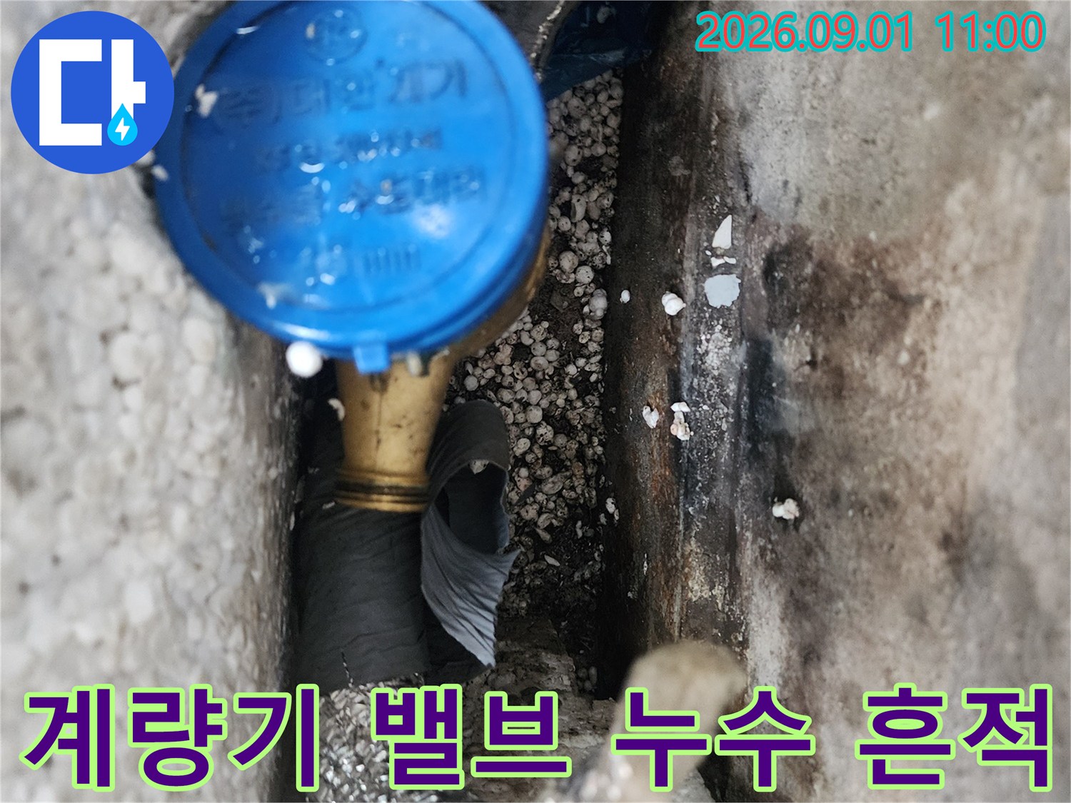 파란색 계량기 밸브와 습기가 찬 배관 연결 부위의 근접 촬영
