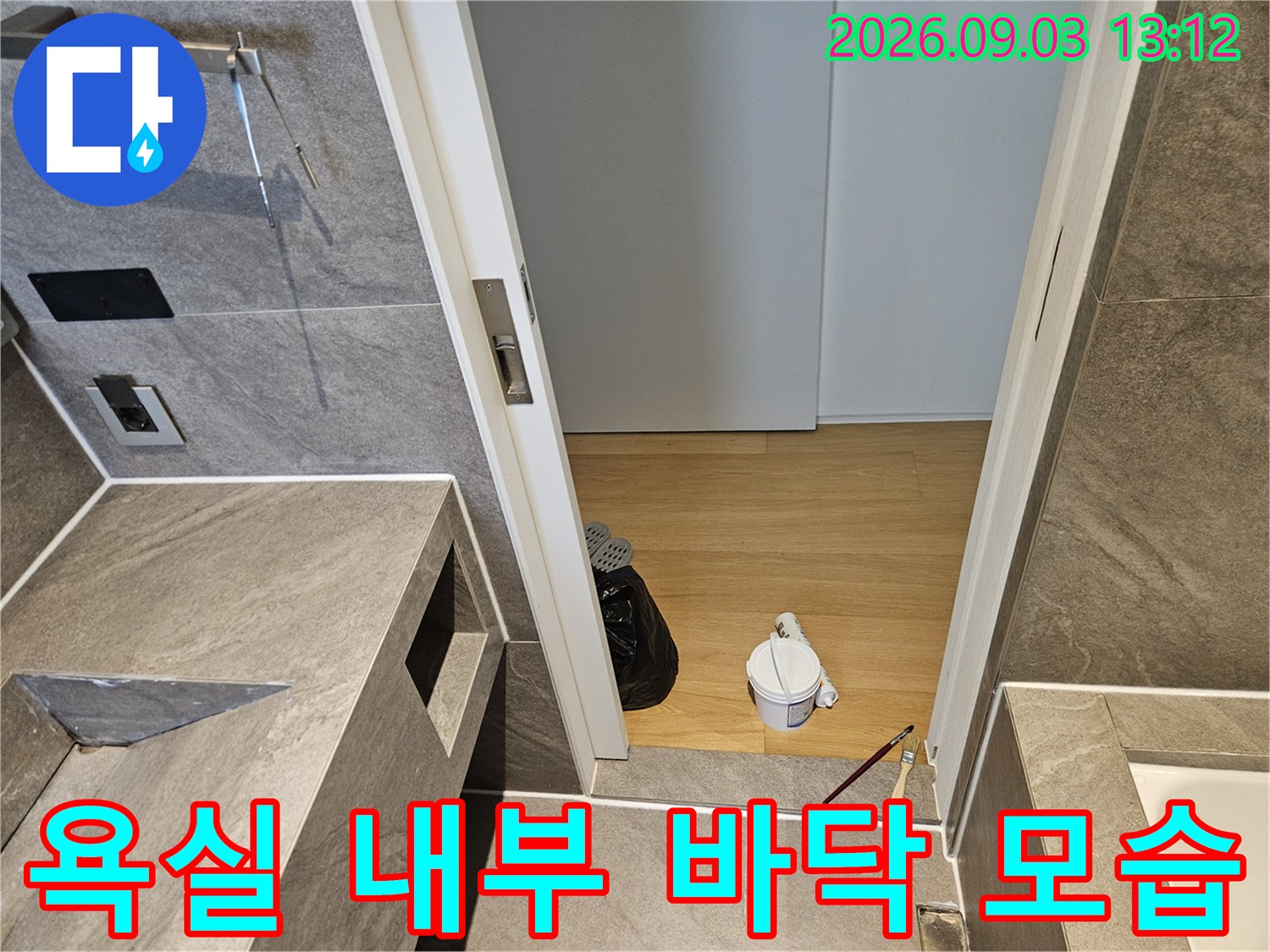욕실 문틈 사이로 보이는 나무 바닥과 설비 도구들