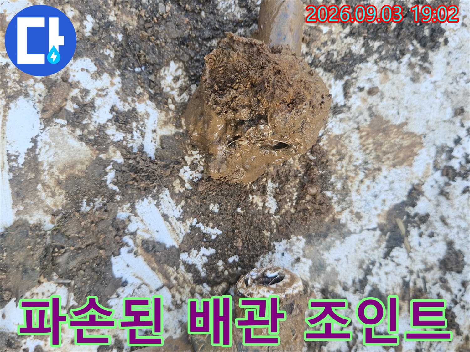흙과 오물이 묻어 있는-파손된 수도 배관 연결 부위 사진입니다.