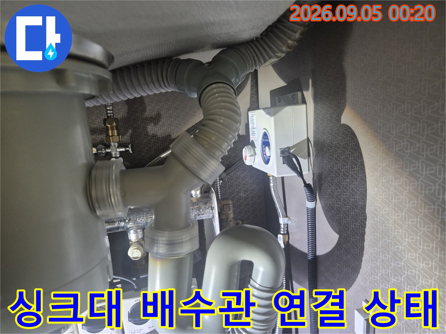 싱크대 하부장의 굴곡진 배수 호스와 연결된 배관 부속 모습