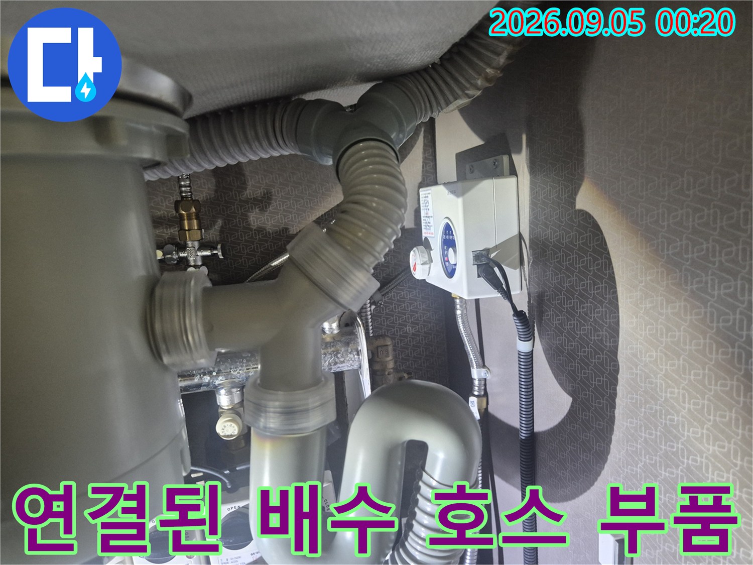 회색 주름관과 하부 관로가 연결된 싱크대 하부 배관 구조