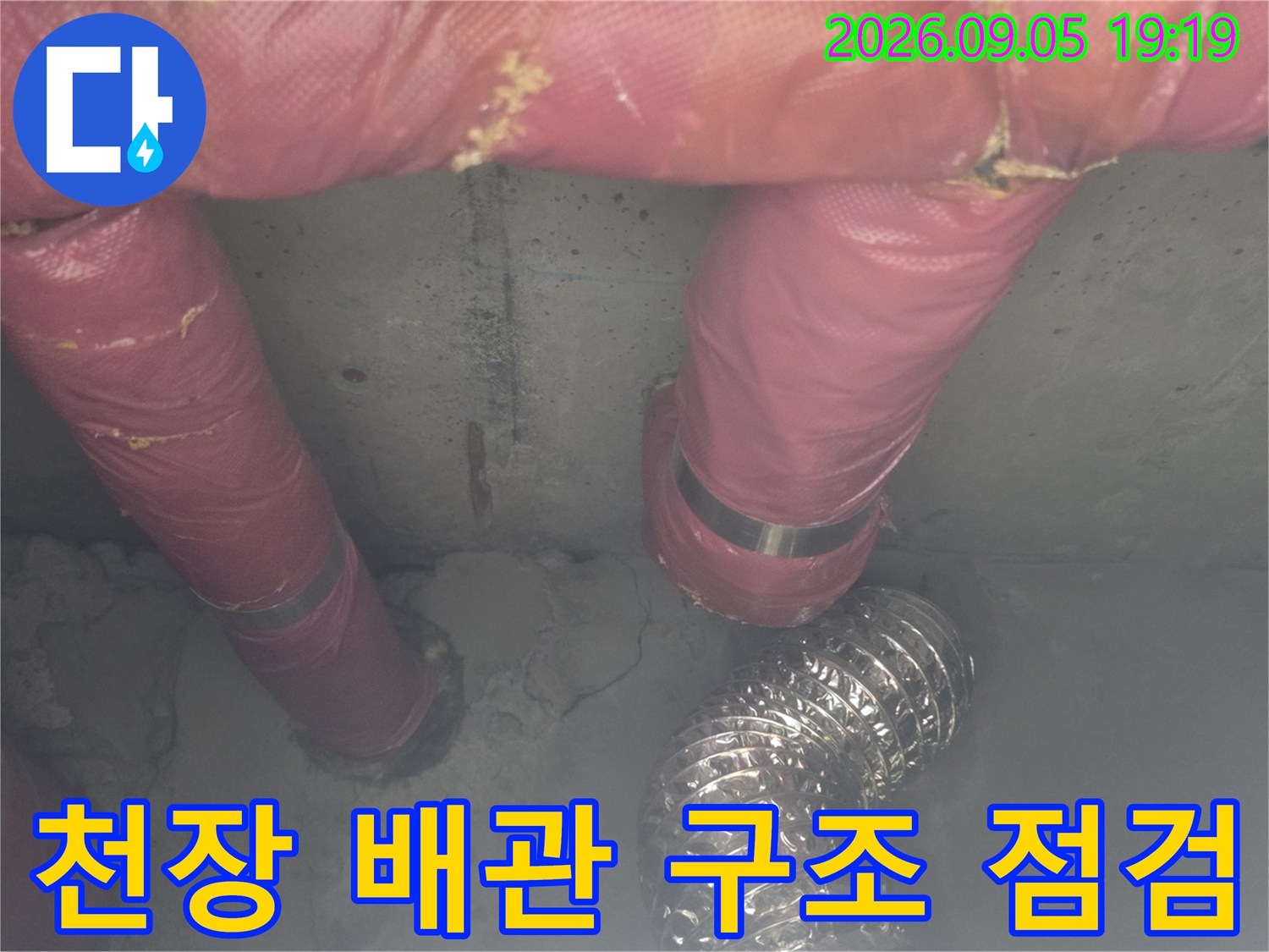 분홍색 보온재로 덮인 배관과 은색 자재가 복잡하게 설치된 천장 내부 모습