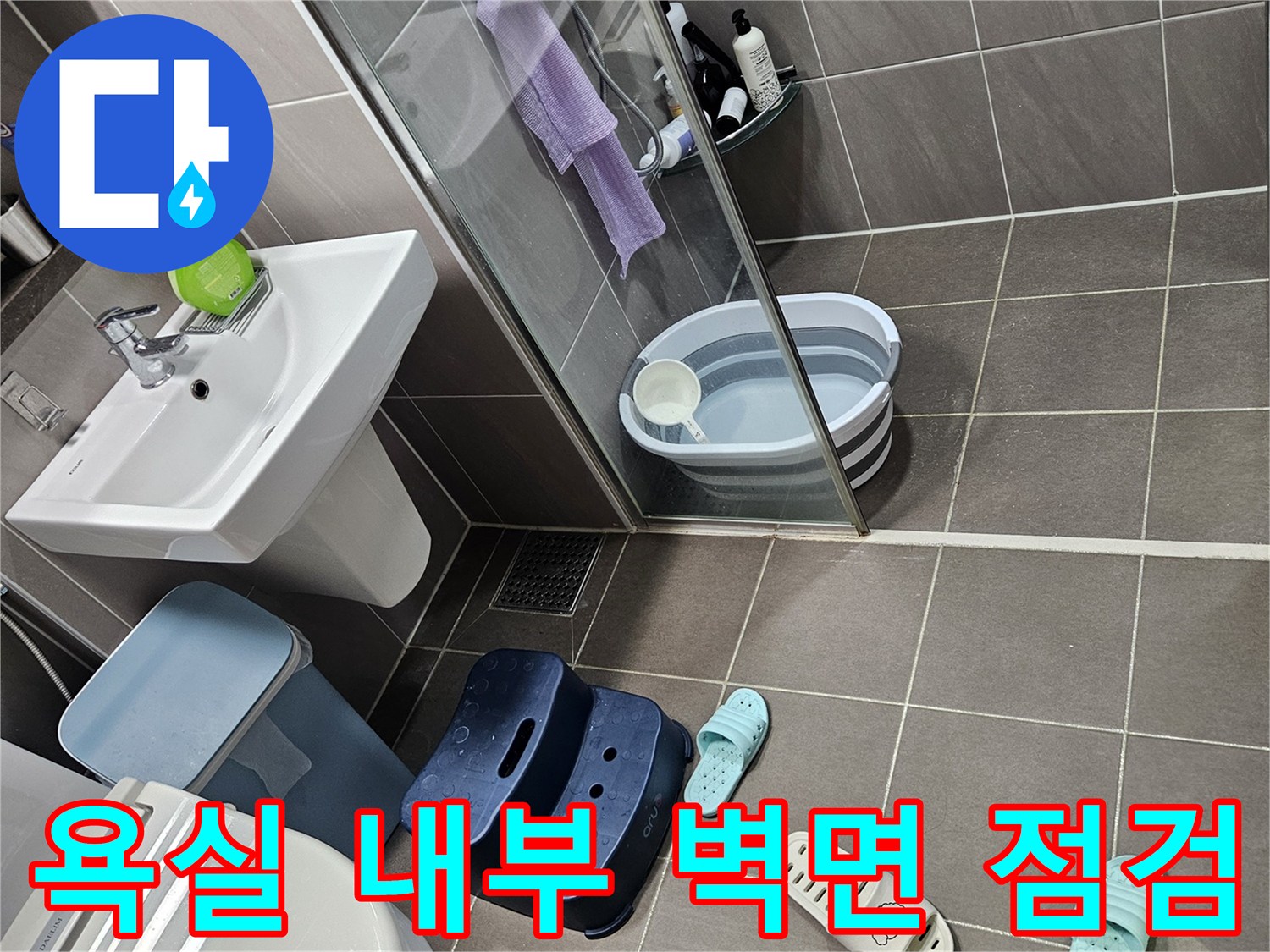 회색 타일로 마감된 욕실 벽과 세면대 하단부 모습