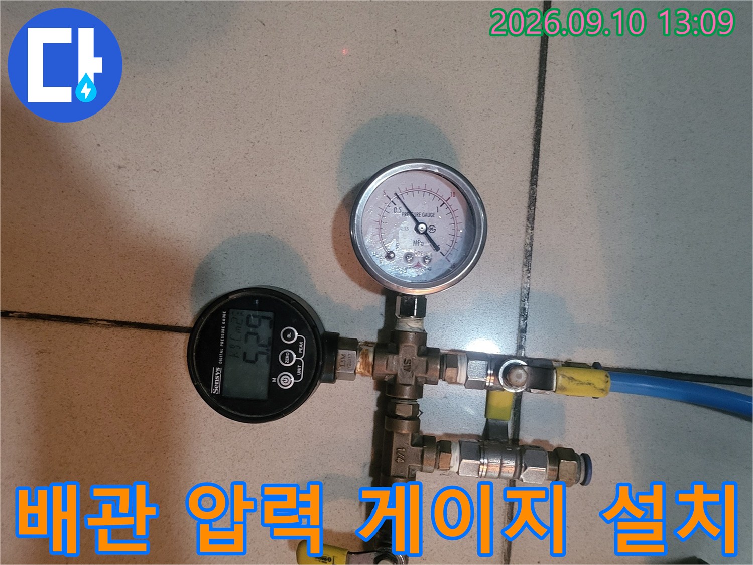 파란색 호스와 밸브가 연결된 배관 시스템의 압력 측정 장비 모습