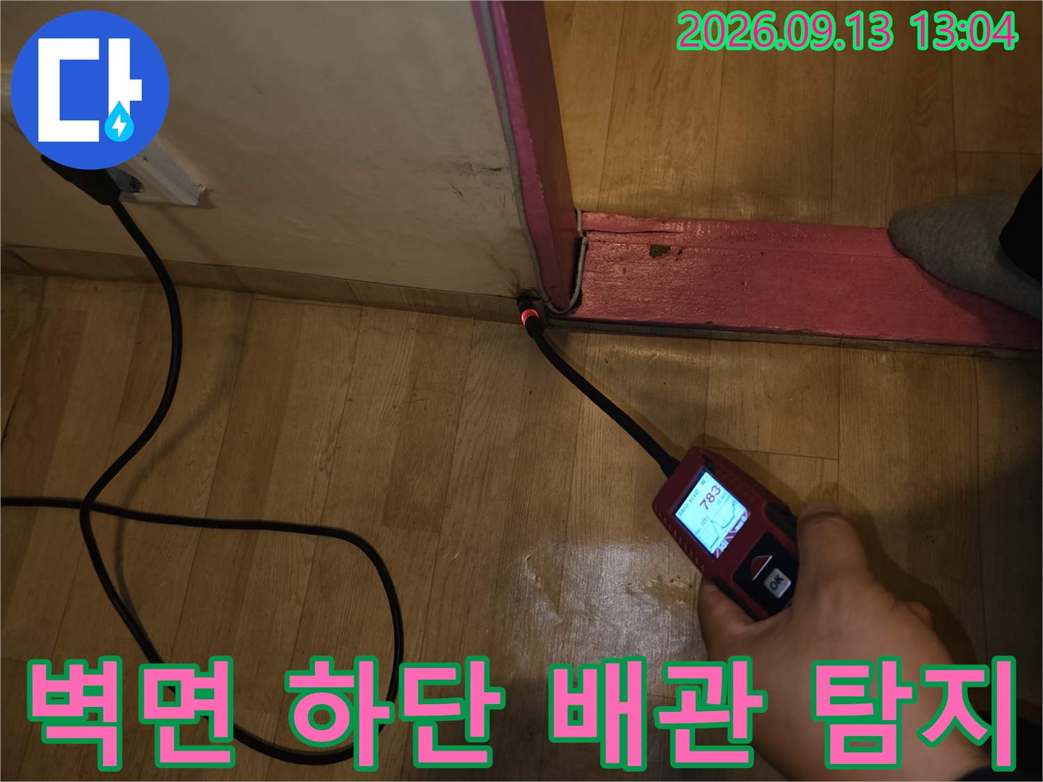 벽과 바닥이 만나는-경계 부위의 누수 여부를 확인하기 위해 장비를 대고 있습니다.